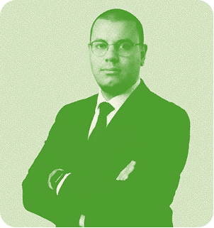 A smiling, bald, African American man wearing a green suit and tie.